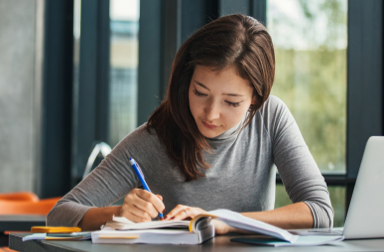 A person sits at a desk taking notes.