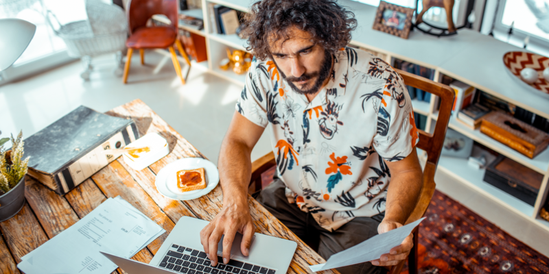 Person working on a laptop and holding a document