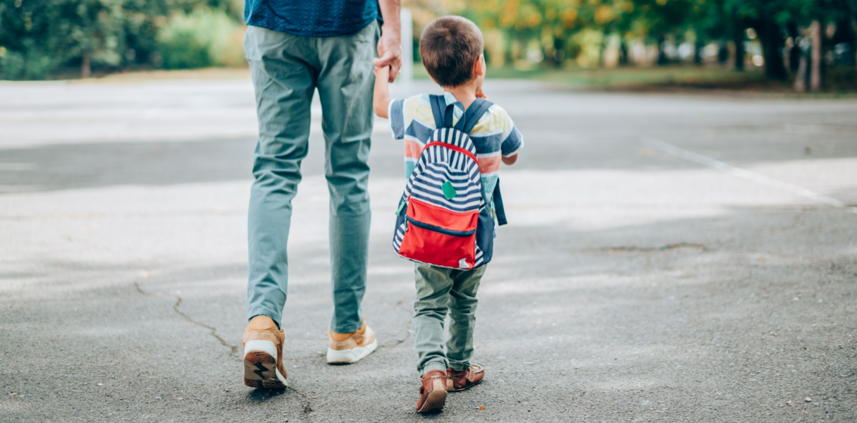 A child walking and holding an adult's hand