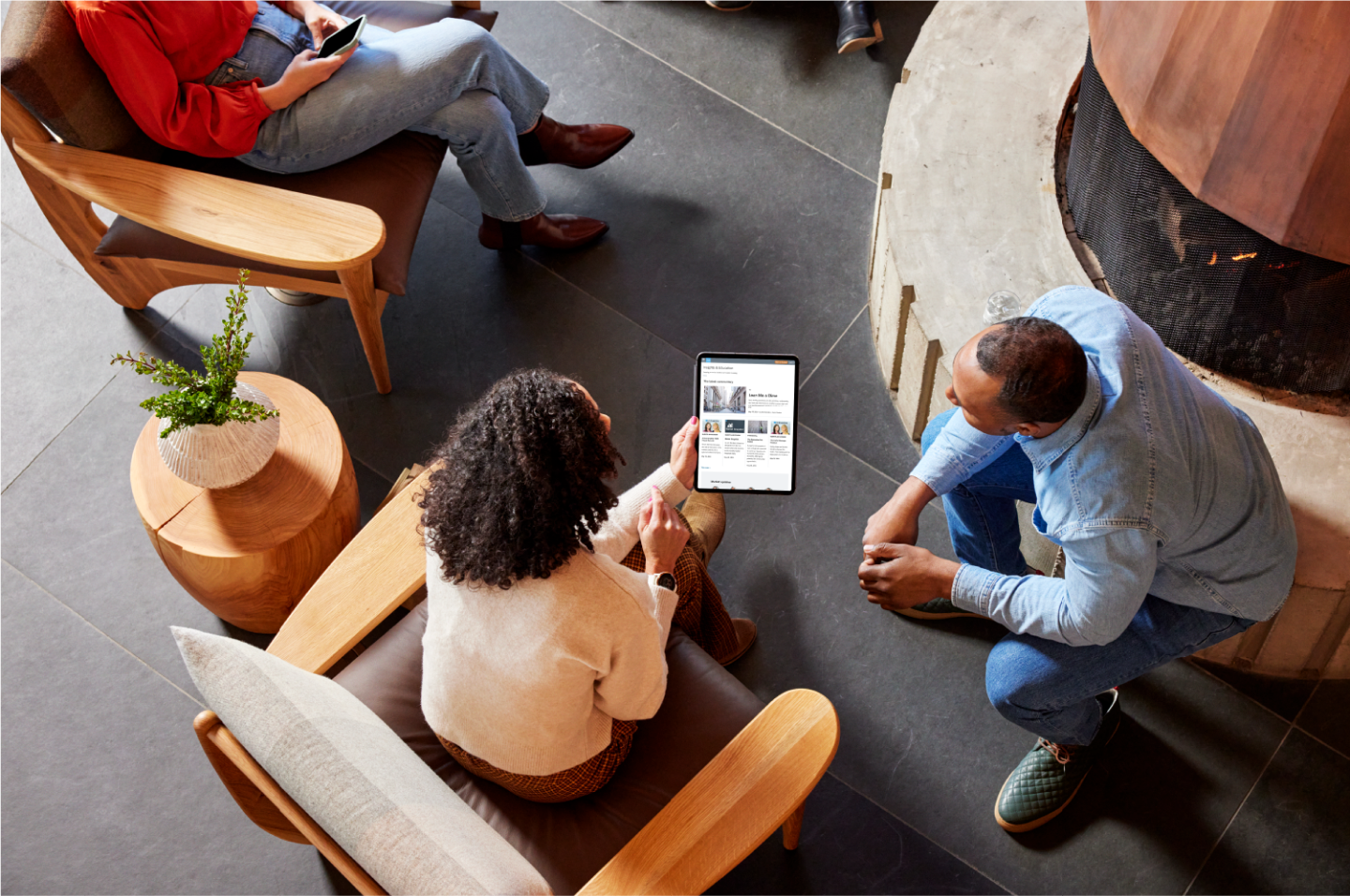 An overhead view of people sitting and looking at a tablet screen that shows the Schwab Insights and Education webpage.