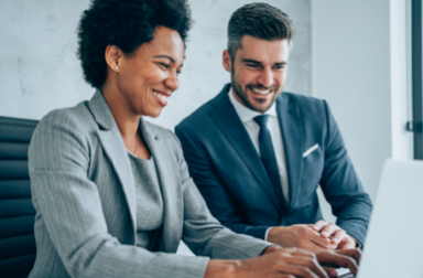 Two business people looking at a laptop, smiling
