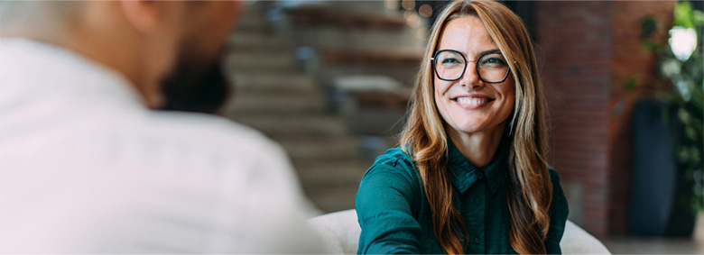 A professional smiling at someone who's in the foreground.