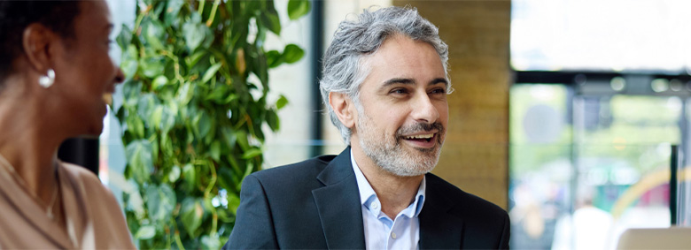 Two professionals smiling and conversing in a building lobby.