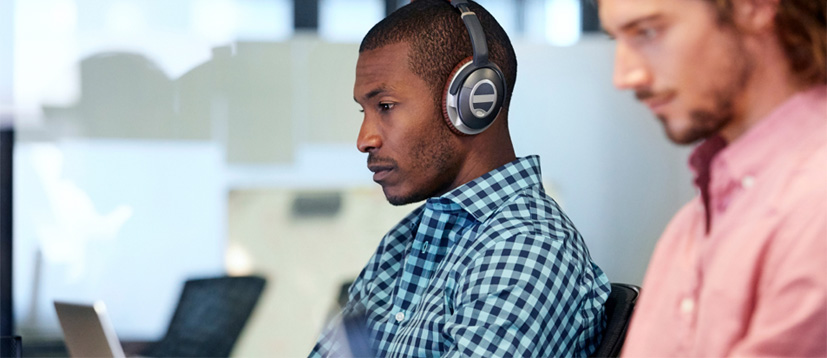 A professional wearing headphones and focusing on their laptop.